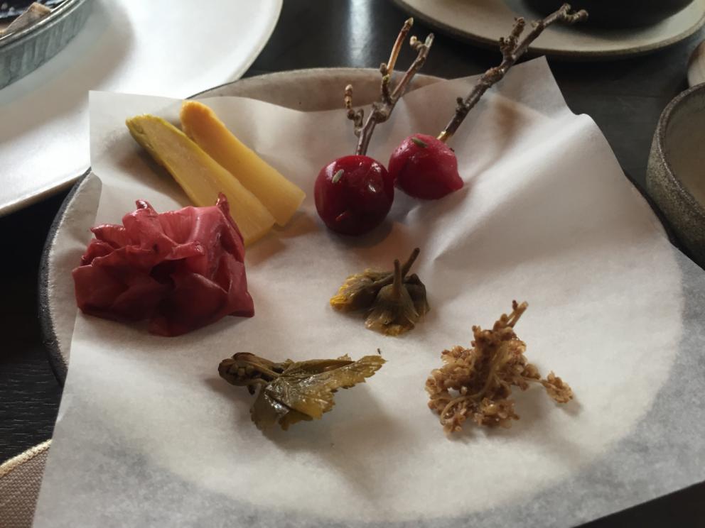 Photogallery






The traditional welcome at Noma: the chefs from the service kitchen greet the guests. In the middle, Italian Riccardo Canella, who will help us describing the last menu in detail (photo gallery by Luca Iaccarino and Gabriele Zanatta)









Warm broth of cloudberries. It’s the last welcome dish at Noma. It’s cold outside but as soon as you sit inside, you get warm thanks to this hot broth made with cloudberries enriched with rhubarb root oil. You dip a bouquet of hay, lemon thyme and mountain pine. Corroborating









Riccardo Canella brings a preview of what will follow









It’s a dish with seafood, including a huge (and alive) king crab, sea urchins and oysters









Apple of the season









Apple of the season. Once you open the shell, many small apple parisienne appear in a juice made with centrifuged, clarified apple scraps, seasoned with verbena and thyme. There’s also a purée of apples fermented in broth. The dish is finished with oxalis flowers, tagete and oil of blackcurrant wood, made by beating the blackcurrant branches with a hammer, so as to extract their essential oils. A very pleasant dish despite its complex idea.

"The first time I saw it ", added Canella, "I was struck because it reminded me of the stuffed apples they used to make at restaurant Bulesca in Selvazzano, Padua, in the early Eighties. Except in that case it was filled with rolls made with granny smith apple and prosciutto from Montagnana" 









Fresh sliced scallop. It’s a scallop taken from the fish tank and shelled a few moments before serving it. It is then sliced, brushed with a reduction of vegetable whipped butter with cucumber centrifuge juice, then reduced, and piso broth (that is to say miso with dehydrated peas).

The technique is the same used for the broth ice-clarification made famous in the Nineties by Heston Blumenthal at Fat Duck: you freeze the broth then hang a table cloth so as to obtain the “pure” part of the liquid. A trick that adds the same satisfying sensation of a meat jus to a vegetable broth. The scallop is finally dipped into a classic mussel broth. An incredible mouthful of seafood and umami









A Winter Platter. Hidden among the leaves, are four edible tastings









He sums up in just one dish 4 snacks that he might would have served separately a few years back. A fun and tasty idea. In detail:

At 6 o’clock: Pear pressed in fermented red gooseberry with fully ripe common sea buckthorn. It’s a rather tart ensemble made sweeter by piso (again miso made with dried peas) seasoned with coriander seeds (supplied by Redzepi’s historic supplier Soren Wiuff). The external thinner leaf is a peel made with chicken broth and beech leaves preserved in vinegar.

10 o'clock: crispy black currant leaf-shaped sandwich, seasoned with yogurt, kombucha, elderberry flowers and red oxalis 

12 o'clock: malt branch with nasturtium leaves, creme fraiche, salt aromatised with pine and ants

4 o'clock: black garlic leaf with salt aromatised with kelp, a Japanese seaweed 









A detail of the malt branch, with well visible ants. At Noma, the study of the aromatic contribution given by formic acid to dishes continues. And even the service acquires elegance: in the past you might have seen ants floating in a few dishes. This is no longer the case









A Tupperware from the "ant library", on the first floor at Strangade









Radish pie. It’s an emblem of the latest menus at Noma. It’s been in the menu for almost a year. In the crunchy disc on the bottom there’s kelp seaweed and a vegetable reduction made with coriander pesto. The radish roses (22, no more, no less) were pressed in beetroot juice. Another formidable tasting









Interns roll the radish roses together, on the top floor at Noma. Loud music and teamwork help making the job less alienating









Natural fermented bread of Øland wheat and hulless barley.  Øland wheat is Danish, with 83% hydration. “Nerd” bread maker Rasmus Kristensen is obsessed with it: even though it could last a week, he bakes it fresh every day for the two services (see the interview on Vice). It has a crispy yet soft crust, and it’s a great progress compared to the early bread making at the restaurant.

The salted butter is instead Norwegian Røros, according to some “the best butter in the world”. One of the most extraordinary pairings ever tasted. We asked for an encore









Cooked oyster and broccoli stems. The oyster is blanched for two minutes and placed on a shell with the edges powdered with salicornia. Between the broccoli and the oyster there are some diced stalks of sorrel. There’s a reduction with kelp seaweed, whisked with butter, thyme and “capers” made with white currants [they’re not real capers but the currants are preserved for a year in 2% salt, like capers). The sauce for the oyster is made with white gooseberries. An artwork, but less convincing than the other tastings









Sea urchin and cabbage. It’s a cabbage leaf pressed with hazelnut oil, filled with sea urchin roe and seasoned with pine vinegar, water from fermented porcini and pickled chanterelle mushrooms. On top, there’s parsley pesto and salt aromatised with pine. It’s a dish that changes greatly according to the season: compared to September, the leaves are now smaller and woodier. Two extraordinary mouthfuls, the result of a rather simple intuition









Sea urchin and cabbage, a detail. Northern sea urchins are creamier than Italian ones. A blast









Langoustine, onion and lavender. The langoustine is the precious one from the Far Oer Islands. The onion is Danish and grilled, steamed in a vacuum bag with Koji oil (blended rapeseed oil with fermented oil) and then grilled again, only slightly, so as to get a golden nuance. The langoustine is instead cooked in its shell, seared in butter at 60°C for 2 minutes, then peeled, cut and served. Rose oil, vinegar made with lovage sprouts and dried lavender complete the picture. The dish is focused on the sweetness given by the onion, which has a similar texture to the langoustine. Very nice









Butternut squash, barley and caviar. The butternut squash is confit in oil aromatised with seaweeds later roasted and placed on top. It is completed with beechnuts, a sauce made with fermented barley and butter and a handful of Finnish caviar. A sweet interlude









Claws and heads of a langoustine from the Far Oer Islands, cut in two. The heads of the langoustine are braised with a paste made with the entrails of the langoustine and a reduction of yeast and thyme and lemon on top. A very pleasing neo-primitive tasting with a strong dose of umami









Steamed king crab and egg yolk sauce. A new take on a classic Japanese dish, learnt in Tokyo and applied in Australia to a snow crab. Global nomadism made Redzepi’s cuisine rounder, less extreme than in the past









In this case, the king crab is steamed and seasoned with smoked salt. The sauce is made with egg yolks marinated in beef garum, a trick that gives a significant sour component to the recipe. Finally, there’s a seasoning made of butter and piso. An interesting depth









Charred greens with a scallop paste. There are plenty of seasonal herbs and vegetables, in this case cabbage, black cabbage, sage, verbena, nettle and the first sprouts of wild garlic. The caramel is made with a purée of fresh scallop, rolled out for 48 hours on a silpat. Once dehydrated, it becomes dark orange. They then blend it, powder it, mix it with bees’ wax and rapeseed oil. Finally they cover the caramel with horseradish juice. Another interlocutory tasting, fun and very much appreciated thanks to the crispiness and the bitter-sweet herbs. Trivia fact: the dish is served with a steak knife. That is to say: herb is the new meat









Roasted Bone Marrow. It’s not the first time they serve grilled bone marrow at Noma, legitimised in fine dining by English Fergus Henderson. What’s new is the way in which they have been serving it in Copenhagen for around one month now: the bone marrow is surrounded by many small plates and garnishes, so guests can enrich it to their liking. A similar idea to what Paolo Lopriore does every day at Portico in Appiano Gentile

 











