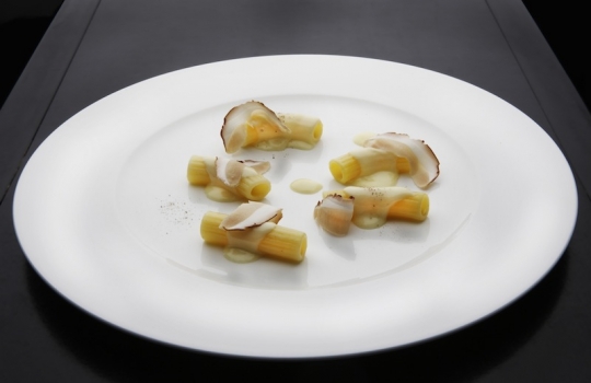 Galleria fotografica






Ravioli di latte di capra con funghi porcini alle erbe (1997)
La madre di tutte le paste ripiene craccobaronettiane.  Genesi 1997, in pieno fermento creativo alle Clivie. "E' il primo esempio di raviolo a bottone - rammenta Baronetto - Ricordo che andavo nel weekend a Giaveno, armato di tanica di plastica a comprare il latte di capra da un piccolo produttore. La cagliata era la farcia del raviolo: a contatto col caldo della cottura il ripieno si liquefaceva». Pasta ripiena d’estro ante-litteram. Un primo tornato in carta spesso negli anni milanesi. Prossimamente con asparagi verdi e tartufo nero (foto Italy behind the obvious)








Spaghetti fritti con composta di pomodoro e basilico fritto (2002)
Gli spaghetti sono cotti normalmente e poi fritti. Interessante la composta di pomodoro impigliata: si ottiene cucinando le solanacee interee in forno, su un letto di sale. Una volta scolate, ne rimane solo la polpa, un concentrato di gusto che poi si trita, condisce e incastra tra i rami di grano duro e il basilico fritto (Foto Bob Noto)








Rigatoni fritti, crema di broccolo e cozze (2003)
Anche qui, la pasta è cotta e poi fritta per un paio di minuti in padella, "come fosse una patatina". Troviamo così per la prima volta i rigatoni, un formato molto apprezzato da C&B: "E' per l'aria, per la cavità che racchiudono: sono belli e intrappolano il condimento, come dei mini-cannelloni" (Foto Bob Noto)








Garganelli d'uovo marinato alla amatriciana (2004)
I Garganelli al ragù sono la prima declinazione della tecnica dell'uovo marinato su un primo piatto: la denaturazione delle proteine del tuorlo, marinato nel sale e nello zucchero, origina una consistenza solida. E' l'affermazione dell'uovo come icona della cucina di Cracco. Dal 2004, la tecnica incontrerà numerose applicazioni ed evoluzioni: vedi il piatto in foto, oppure i celebri Spaghetti d’uovo marinato, ricci di mare e caffè (2009). E un terzo esempio ancora più recente alla fine di questa stessa gallery (foto Made in Photos)








Paccheri di gruyère (2004)
Un esempio di pasta non-pasta, un filone che negli anni ha coinvolto diversi cuochi (poco, a dire il vero, C&B). "Pasta non-pasta" perché, in questo caso, i paccheri non sono di grano duro ma di gruyère, formaggio svizzero. Il "pacchero" è servito su un'insalata. E' un piatto d'intermezzo, non confinabile al regno dei primi (Foto Bob Noto)








Tagliatelle di patate, alici e broccoli (2004)
Le tagliatelle sono in realtà gnocchi dalla forma allungata. Sono lasciate asciugare in cella e cotte normalmente. Il gusto è più dominante di quello di una tagliatela all'uovo. In stagione, ben accette le lamelle di tartufo (Foto Bob Noto)








Ravioli ripieni di maionese con ricci di mare e semi di basilico (2006) 
Evoluzione del piatto partorito alle Clivie (1997), non è un raviolo ma un bottone. E' fondato sul concetto di sottrarre pasta, il bordo del raviolo che comunemente eccede. E il condimento diventa contenuto, altro topos del procedere craccobaronettiano. In questo caso, la maionese è appena intiepidita (ma non si scioglie) ed esprime tutta la sua godibile grassezza e condimento (Foto Bob Noto)








Ravioli di broccoletti cotti sul rosmarino, semi di basilico e frutti di mare (2008) 
Un raviolo ottenuto con una tecnica interessante perché è cotto per affumicatura sul rosmarino. E così anche i frutti di mare, che cuociono per calore indiretto (foto Paolo Marchi)








Rigatoni, lattuga alla liquirizia e burro all'olio grattugiato (2009) 
Il burro all'olio è un altro importante capitolo della saga, aperto con l'ultima edizione de Lo Mejor de La Gastronomia ospitata a San Sebastian (ora è Alicante): Matteo Baronetto vinse il concorso internazionale dedicato all'extravergine di oliva con una Crema bruciata all'olio di vaniglia, seppia e garusoli. La vera novità è in quell 'burro all'olio', burro di cacao e olio crudo raffreddato, in questo caso grattuggiato sopra a rigatoni freddi, in una sorta di insalata di pasta con condimento semisolido e lattuga impanata nella polvere di liquirizia. Un altro scintillante antipasto/intermezzo (foto Brambilla/Serrani)








Timballo del Gattopardo (2009)
"Va bene l'uovo marinato e tutto il resto: ma perchè non provate a cimentarvi col Timballo di Maccheroni del Gattopardo? Quella sì è una ricetta coi contro*****", provocò il cliente gourmet. Non dirglielo due volte a C&B che son già lì a studiare e provare. Il risultato è in questo magnifico timballo che, più che sottrarre, stipa: rigatoni cotti, salsa al pomodoro, piselli, prosciutto, funghi secchi, rigaglie di pollo e coniglio... "cintare e tappare di pasta frolla tutto questo era già indice di grande creatività", commenta Baronetto, "del resto i Siciliani, già nel Seicento cucinavano l'anguilla con il coniglio"  (foto Altissimo Ceto)








Ravioli vegetali in pasta di riso su brodo di patate arrrostite (2010) 
Altri ravioli fatti a bottone, sono figli della fascinazione per la pasta di riso per celiaci di cui iniziano ad abbondare i supermercati: "Perché non utilizzarla come una pasta fresca qualsiasi? Ci siamo chiesti", racconta Baronetto, "il problema è però legato alla tenacia; è un prodotto facile a disfarsi, a meno che non la leghi con un po' di albume e latte" (della stessa famiglia, sono finiti in carta anche i Tagliolini di riso con caviale in insalata). E il brodo? E' un'infusione di patate arrostite crude su piastra (foto Arthur Angry)





