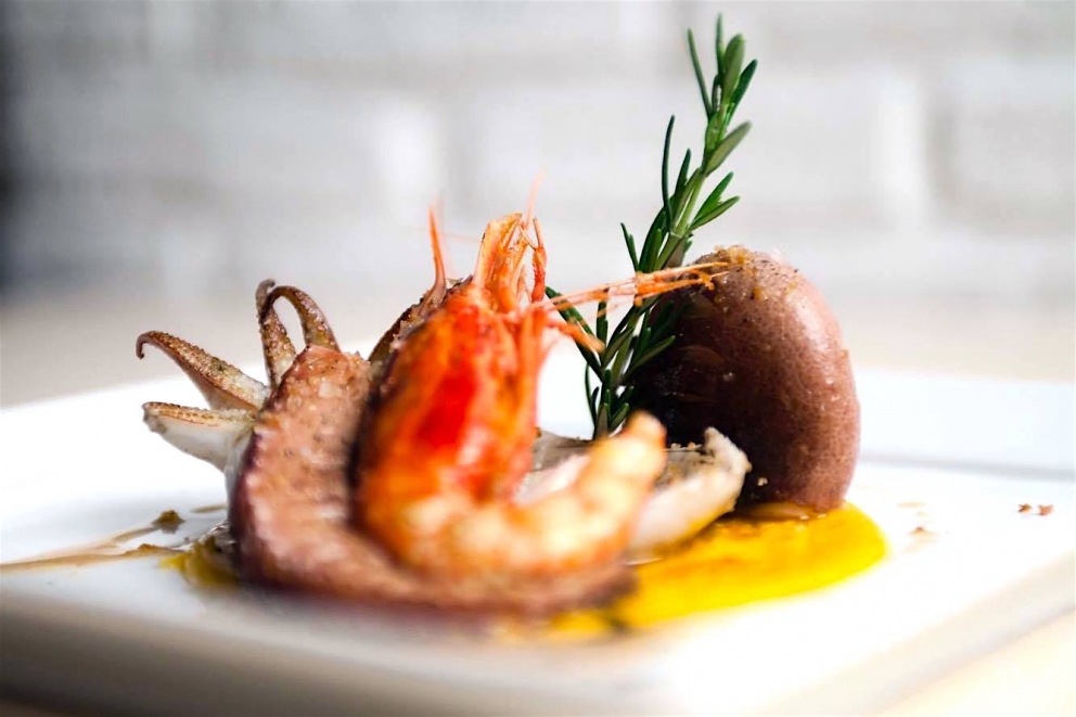 Galleria fotografica






Giuseppe Causarano, Locanda Gulfi, Chiaramonte Gulfi (Ragusa)

Palamita affumicata con foglie di vite, melagrana e azzeruole - Il piatto nasce dalle escursione sul letto del fiume Irminio, territorio sconosciuto e incontaminato che si addentra tra i Monti Iblei e sfocia a Donnalucata, dove poter raccogliere frutti, fiori e erbe selvatiche. Racconta la biodiversità di una terra fantastica come la Sicilia, lavorando uno dei pesci cosiddetti "poveri" come la palamita utilizzando dei prodotti dimenticati come le azzeruole. Il supporto del piatto disegnato da me e realizzato da un artigiano di Modica Giovanni Cerruto ricorda i ciottoli del fiume Irminio









Pino Cuttaia, La Madia, Licata (Agrigento)

Memoria visiva - E' il mio ricordo in una fetta di tonno rosso di Sicilia. Quando ero piccolo mio nonno, che era un ottimo cuoco, marinava con un po' di limone la paillard di vitello, prima di cuocerla. Faccio lo stesso col tonno, ma non lo cuocio anche se l'aspetto è simile, l'impressione della cottura è data proprio dalla marinatura. Se capita lascio che si trovi nel piatto anche il seme del limone: le mamme non si curavano mai se qualche seme cadeva nel piatto. Così presento la ricetta con una volontà evocativa di una quotidianità familiare, che è vita






