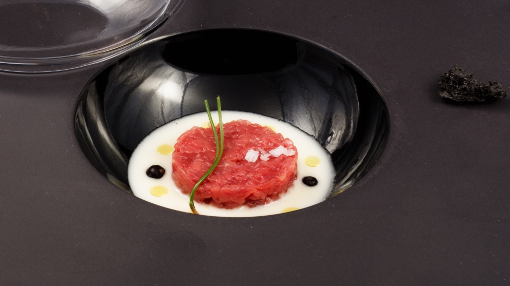 Galleria fotografica






Di grande complessità il Crudo di gambero rosso con stracciatella di burrata al pepe nero e centrifuga di pomodoro datterino al basilico, caviale di storione e polpa di ricci, sferzante, tonico, di mare in tempesta e di terra feconda. Da non perdere per alternanza di tendenze dolci, acidità eterogenee, speziatura e sapidità









La Vitellina a punta di coltello con fonduta di formaggi cremosi e bacche di ginepro dell’Etna affumicata agli aghi di pino investe tre sensi: per la vista è un’immagine evocativa della Muntagna, col rosso della carne al centro a simboleggiare la lava e il bianco della fonduta a rappresentare la neve; per l’olfatto è inebriante il fumo di pino che si diffonde nell’aria quando si solleva la cloche; per il palato è la gioia di un piatto intenso e polposo, bilanciato nella cremosità e nelle acidità silvestri e impreziosito da un delicata affumicatura al ricordo di bosco






