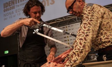 A sinistra, Kobe Desramaults di In de Wulf spacca e sega una testa di cinghiale: è il piatto di un cervello rosolato al burro. A supporto, il presentatore Andrea Petrini (foto Alessandro Castiglioni)