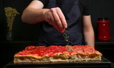 Sono le mani di Daniele Campana, impegnato a perfezionare una delle sue pizze in teglia. Con le sue insegne di Corigliano Calabro (Cosenza), Campana Pizza in Teglia e Campana 12, ha ricevuto dalla nostra Guida il Premio Creatività per il 2024
