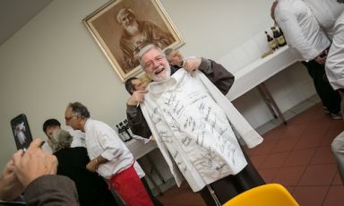 Padre Maurizio con la casacca firmata da tutti i cuochi che hanno cucinato al pranzo benefico dell’Opera San Francesco per i Poveri, in viale Piave a Milano ieri, domenica 27 ottobre (foto Dino Zanolin)