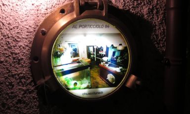 A detail of the entrance to Al Porticciolo, the restaurant opened in 1984, in Lecco, by the Ferrari family, in Via Fausto Valsecchi 5, tel. +39.0341.498103. It is because of this very date that on the porthole there’s written Al Porticolo 84. Fabrizio Ferrari, born in 1980, starred chef since the 2004 edition of the Michelin Guide, has never betrayed the vocation of his parents for a seafood cuisine, except he transforms it following his ideas and experiences. The dishes that made the fortune of this restaurant during the last century are not missing. Therefore, two ways of cooking fish share the same roof