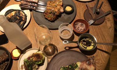 La tavola imbandita al ristorante Barr di Copenaghen con le portate principali del menu degustazione, e quindi il Prosciutto arrosto, con fondente di patate e due varietà di tartufi locali e Scorfano, con bacon di cinghiale, verza grigliata e fragole verdi fermentate
