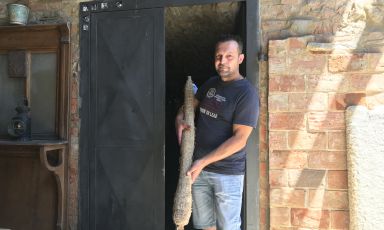 Fabio Zanotti, detto il Cianta, sull'uscio della sua cantina quattrocentesca in alta val Curone dove custodisce prelibetezze come quella che tiene in mano, un salame tipologia "gentile" vecchio almeno quattro anni
