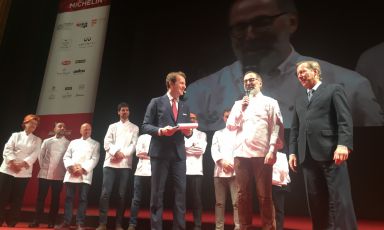 Il momento clou: Norbert Niederkofler riceve la terza stella dalle mani del direttore internazionale delle Guide Michelin, Michael Ellis, sulla destra. Dietro di loro gli altri otto tristellati, tutti confermati
