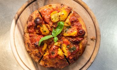Anna Daniele, la pizza che Giuseppe Maglione, patron e pizzaiolo della pizzeria Daniele Gourmet, ad Avellino, dedica a sua nonna: viene cotta nel ruoto - la teglia di alluminio tonda - e condita con 4 varietà di pomodori campani, aglio Orsino, origano, basilico e olio Evo
