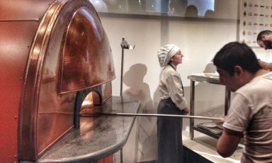 TheScugnizzo electric oven at Identità di Pizza 2015. Cristian Mastroianni, Franco Pepe’s collaborator, is handing the peel. The oven is produced by Izzo forni, a Neapolitan firm founded in 1951. Scugnizzo has the same performance as a wood oven, without its disadvantages 