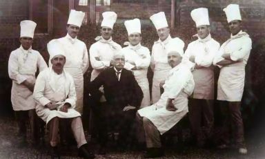 Il grande cuoco francese Georges Auguste Escoffier, baffuto al centro, con giacca e cravatta, posa insieme alla sua brigata di cucina. Fu lui a pensare allo staff di un ristorante governato dalle stesse logiche che caratterizzano le unit&agrave; militari. &Egrave; per&ograve; un modello che appare sempre pi&ugrave; antistorico
