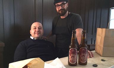 Alessandro Pipero seduto dietro al banco all'ingresso del nuovo ristorante che a Roma ha preso il posto del Pipero al Rex vicino alla Stazione Termini. In piedi accanto a lui lo chef Luciano Monosilio
