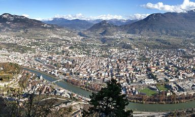 Una visione panoramica di Trento: la città, come illustra Alfio Ghezzi, è ricca di insegne degne di nota, come il ristorante Scrigno del Duomo dello chef Alfredo Chiocchetti o l'Enoteca Provinciale ospitata all'interno di Palazzo Roccabruna