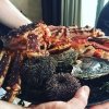 E' un piatto con crostacei e conchiglie tra cui un enorme king crab ancora vivo, ricci di mare e ostriche
