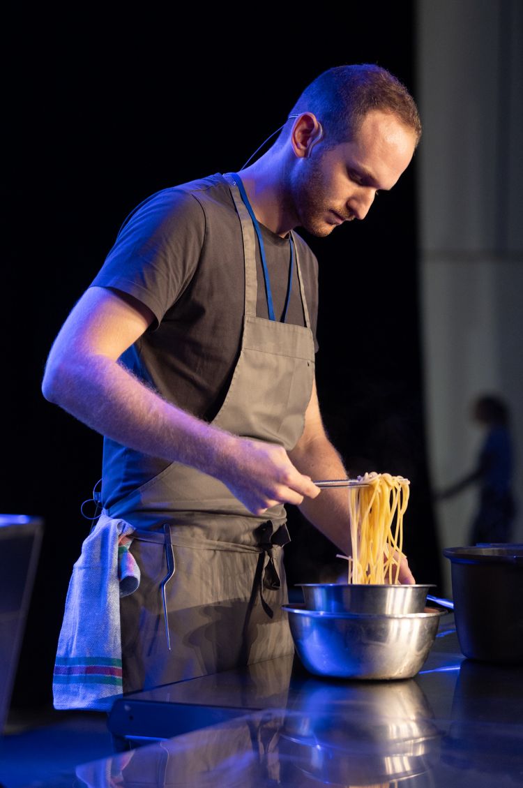 Il sous di Contrada Bricconi, il trentino Stefano Gasperi, sul palco di Andorra Taste, mentre prepara lo Spaghetto freddo, grasso di trota e rabarbaro
