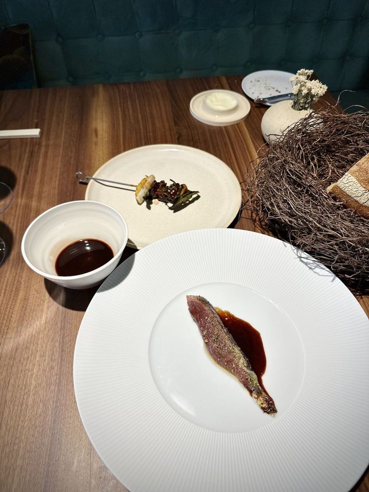 Germano in più servizi: si parte dal petto, rivestito di lardo, con il suo fondo di cottura e un geniale sciroppo di cacao fermentato. Poi c'è un brodo realizzato con gli scarti del germano stesso, rapa rossa e pepe lungo. Infine, arriva un eccellente Spiedino di interiora, salvia, mela cotogna e cipollotto