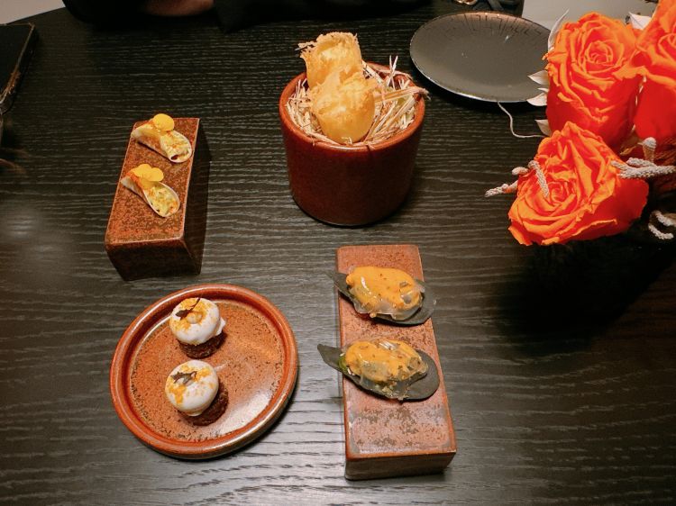 Amuse bouche: Cialda al nero di seppia, cozza farcita con peperone crusco e ricoperta con gelatina di acqua di cozze. Uovo di quaglia in tempura, soia, limone e rafano. Cupolina di broccolo romanesco glassato con latte di cocco, servito su pane di segale e completato con crema di acciughe. Taco fatto con una sfoglia sottile di daikon: all’interno patè di tonno e guacamole
