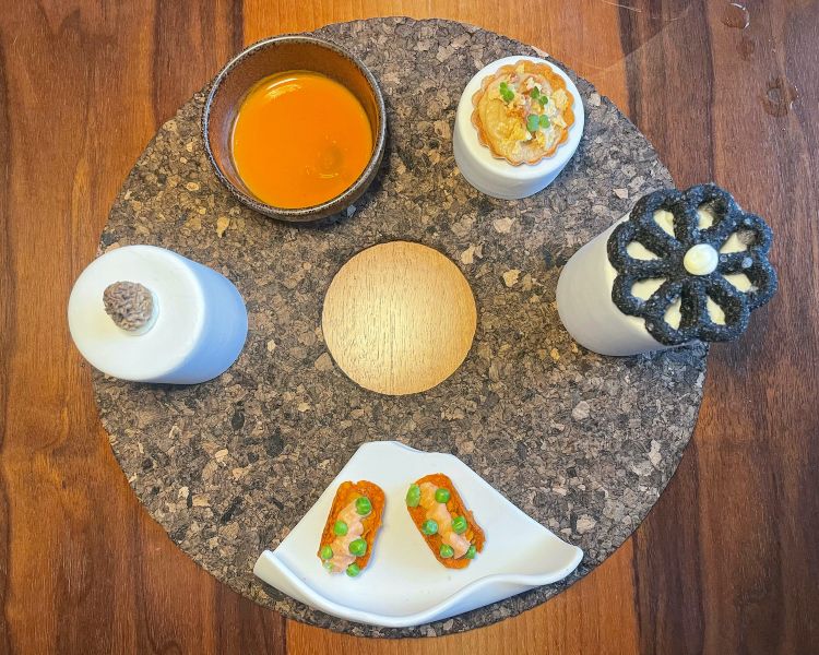 Amuse bouche: Spugnola e il suo cremoso. Gazpacho con olio al lemongrass e basilico, Tartelletta con cipolla caramellata, chips di cipolla e parmigiano, Fiore croccante al carbone vegetale e cremoso al tartufo e Tacos: Il ricordo della paella de Marisco