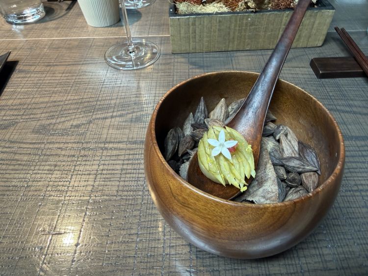 Appetizer in apertura, micronizzati alla maniera occidentale. Oliva verde del Guangdong con amla (uvaspina) e balsamo di limone. Semicoperta alle spalle, una tartelletta di zha guang jiao dal Wuhan (peperoncino fermentato con farina di riso) e una foglia di huo xiang (menta coreana) e noce macadamia