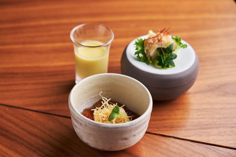 Sakizuke
L'esordio della cena coincide col primo piatto composto del menu kaiseki. A destra, nanbanzuke, in questo caso un pesce prete (uranoscopus scaber, pesce di fondale) preparato in una sorta di carpione (infarinato, fritto e marinato nell'aceto) e servito su foglia d'acero; sotto gomadofu (tofu con pasta di sesamo e tè verde tostato) e sopra del surinagashi, una zuppa leggermente gelatinosa di mais