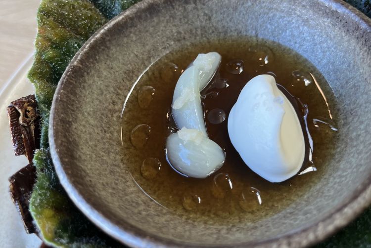 New season garlic and onion
A gelatine of mushroom broth and onion on which, to the left, is placed some young, blanched garlic, cut and seasoned with oil of red fir and plum stone. The quenelle to the left is whipped cream

