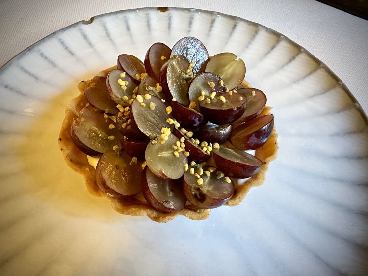 Tartelletta di pasta viennese, cremoso alla ricotta di capra e cioccolato bianco, polline e uva: ben fatta, è una bella carezza finale