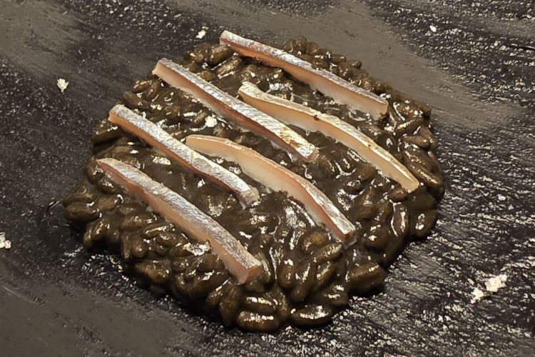 Pescatori d’argento: riso cotto in dashi al nero di seppia con alici marinate nella propria colatura. Piatto ispirato agli scenari della pesca notturna delle alici