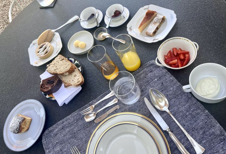 The magnificent breakfast at the Argine di Vencò. On the table, clockwise from left: apricot jam buchtel, sourdough and chocolate bread, strawberry jam tartlet, salted butter, sulla honey, apple juice, plum and strawberry jam, cheesecake and strudel, strawberries, yoghurt
