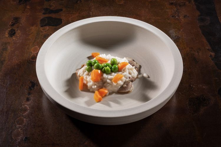Risotto mantecato in emulsione di mandorla, con piselli, porri, carote novelle di Ispica, agnello, coniglio, timo e rosmarino: la meraviglia dolce-salata di Corrado Assenza
