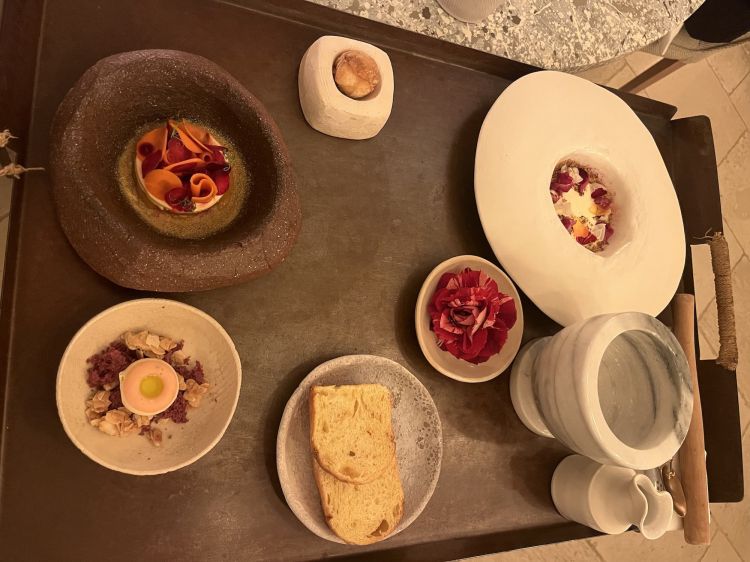 Ciambellina di ravanello in agrodolce di olio e mandorla, Lampascioni, farinella e cioccolato fermentato, Cremoso alla vaniglia, opunzia e rosa, Brioche allo zafferano e arancia con granita di kombucha ai petali di fiori... anche i dessert, curati dal pasticciere Tiziano Mita, risentono di una forte impronta vegetale e del contributo delle sementi quasi dimenticate