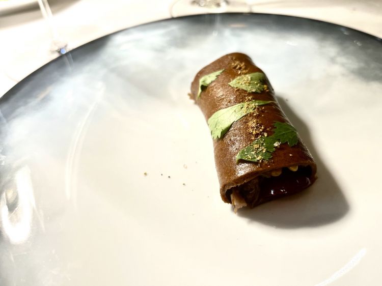 Coda di bue brasata, ciliege, cerfoglio e cumino
Di solito il ponte tra pietanze salate e dolci arriva col pre-dessert. In questo caso è un secondo ad amalgare note dolci e sapide nello stesso piatto, anticipando le dolcezze crescenti del finale. La coda di bue alla vaccinara arriva qui con le ciliegie al posto delle uvette e il cacao si trova nell'impasto simile a un bignè, ma cotto a vapore, come un biscotto morbido. All'interno coriandolo e cumino richiamano gli stufati della tradizione persiana e nord-africana, carne chiusa spesso da impasti morbidi e dolci. Brezze mediorientali in Galleria
