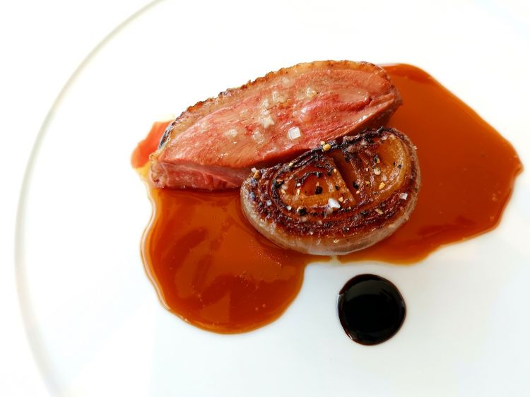Anatra con cipolla rossa cucinata nel forno di argilla. Come accompagnamento, insalata di cipollotto e peperoncino, tartina di ceci con mousse di anatra e foglie di shiso rosso