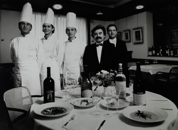 Una foto storica e celebre: un giovanissimo Igles Corelli, primo da sinistra, con Marcello Leoni e Bruno Barbieri; al loro fianco il patron Giacinto Rossetti con il maître Bruno Biolcati. Tutti insieme a Il Trigabolo di Argenta, storico e rivoluzionario ristorante. Tutto iniziò nel 1979 quando il rappresentante di giocattoli Rossetti con il socio Gualtiero Musacchi rilevò una pizzeria in piazza Garibaldi 4b, ad Argenta, chiamando un giovane cuoco che aveva lavorato sulle navi, tal Igles Corelli...