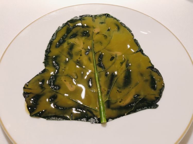 Foglia di broccolo e anice: la foglia è sbollentata in acqua e sale, per esaltare di più colore e sapore, mentre la glassa è data dal fiore del broccolo, con gocce di anice. Piatto-simbolo della svolta vegetale di Niko Romito, è diventato ormai un’icona naturale
