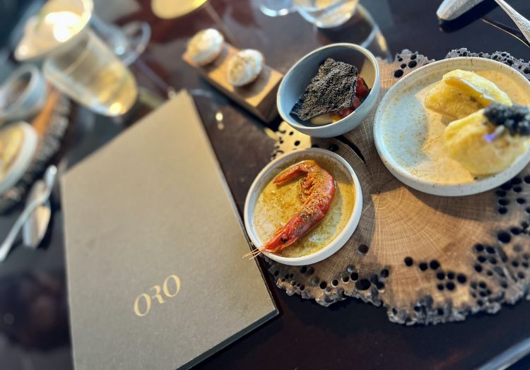 I menu degustazione del Ristorante Oro, contenuto nell'hotel Cipriani, sono due: "Una nuova primavera" e "Vegetum", quest'ultimo interamente vegetariano, rispettivamente 250 e 200 euro (più 170 euro, l’opzione abbinamento vini). Lo apre una frase, Unde Origo Inde Salus, "Dall'origine proviene la salvezza", lieve variazione del motto molto caro al cuoco padovano: "Libero è colui che ha radici profonde". Tra le entrée del menu colpisce un assaggio che è sintesi di quello che vedremo: Fiore di zucca ripieno baccalà mantecato all’olio di koji, con miso di polenta. Passato e futuro del ragazzo in un boccone
