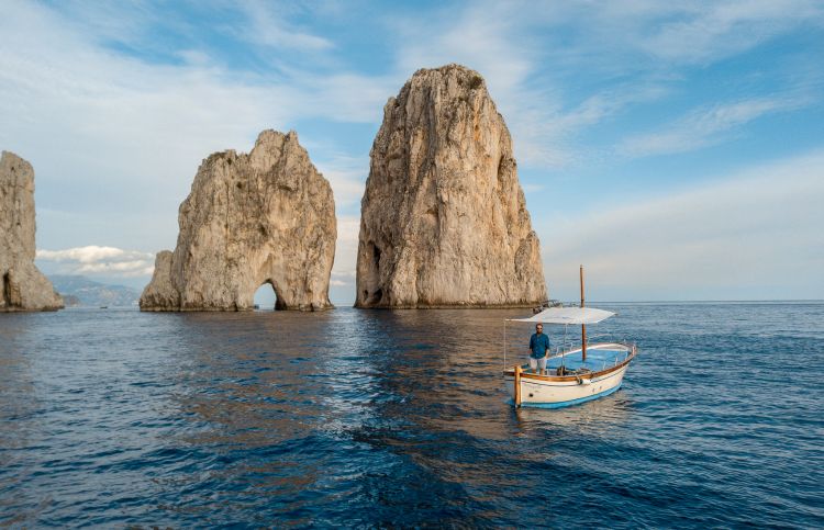 Il gozzo di Mare Mio accanto ai celebri faraglioni di Capri
