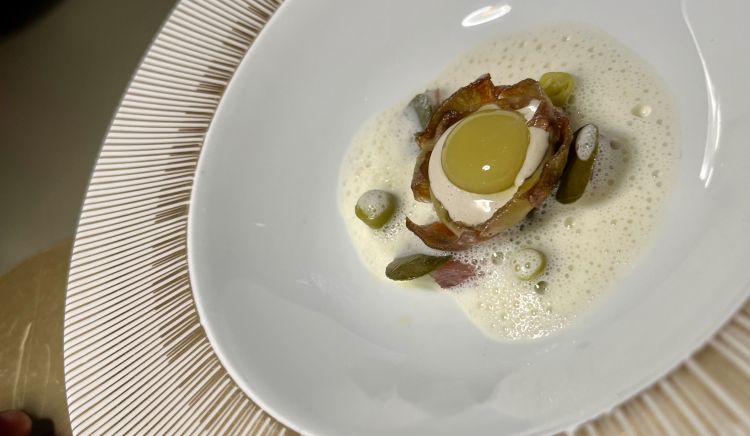 Carciofo fritto, sardina affumicata, oliva verde, piparra ed emulsione di burro nocciola (Sacchi)
I carciofi, strappati dall'orto pugliese da 3 ettari di proprietà del Circolino di Monza, sono il perno attorno a cui ruota una rivisitazione della gilda, uno dei pintxo più popolari di San Sebastian, variabile ma composto di solito da peperoncini piparra, acciughe e olive. Nella versione di Sacchi c'è un carciofo confit e poi reso croccante, con all'interno crema di sardine e un'oliva sferificata. Sulla base, ad aggiungere sapidità, poggia una crema di carciofi con scalogno e brodo di cozze e il trio di ingredienti della gilda, con fiori di cappero e burro nocciola. Complessità, gusto, gola. Curiosità: i piparra nessuno li coltiva in Italia, così Lorenzo se li fa arrivare direttamente dalla sua patria elettiva
