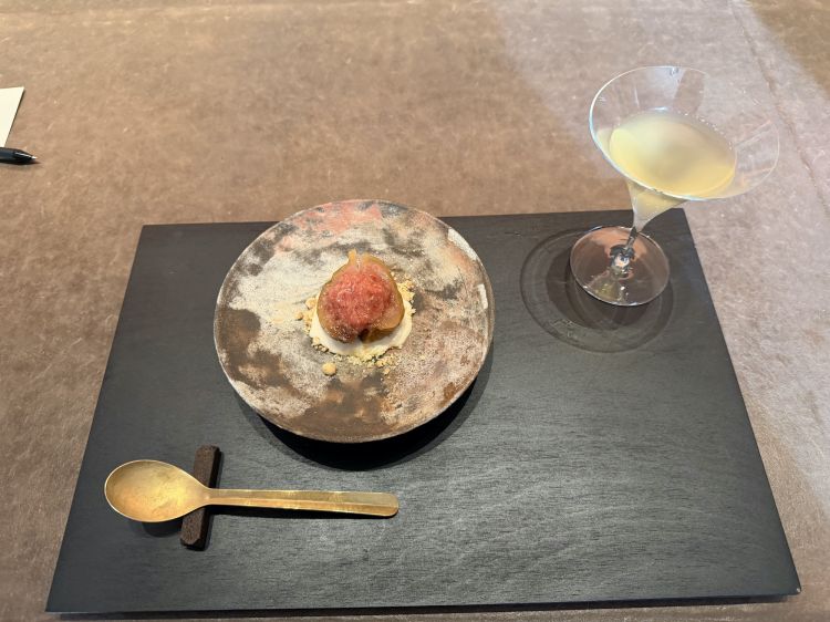 La coppa contiene un mocktail di alchechengi fermentato, in pairing con mezzo fico su una salsa di erba pechinese, salsa di fagioli e aceto d’uva