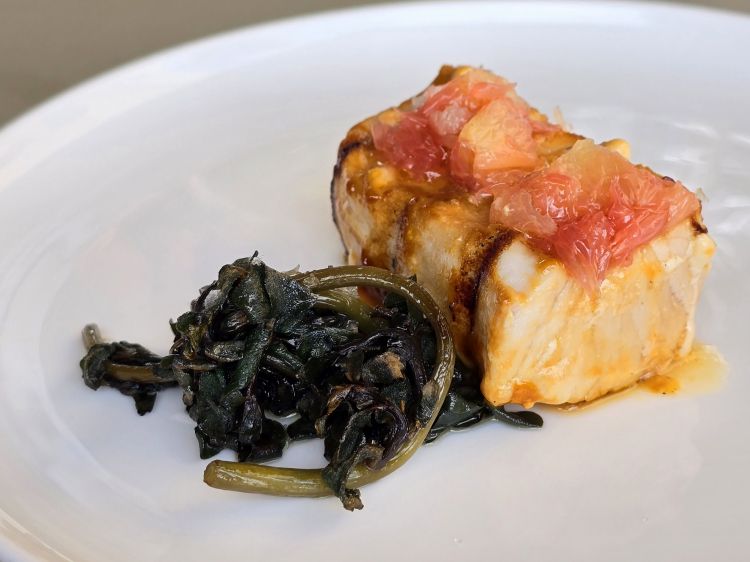 Pesce spada frollato con pompelmo e portulaca. Il pesce spada viene frollato per 8 giorni, cotto al Josper con una laccatura di pompelmo e soia e servito con portulaca. La frollatura conferisce al pesce una texture più tenera, intensità di gusto e succulenza, quest’ultima ampliata dall’acidità dell’agrume. Non mancano sfumature dolci e umami e una leggera e piacevole affumicatura. A chiudere le note fresche e acidule della portulaca