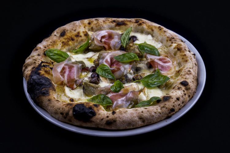 Pizza con carciofi di Albenga e pancetta. La tecnica è quella della verace napoletana, «panetto da 260 g, impasto diretto, lunga maturazione... Il gioco qui era incrociare la tradizione partenopea e i prodotti della Liguria, il territorio»
