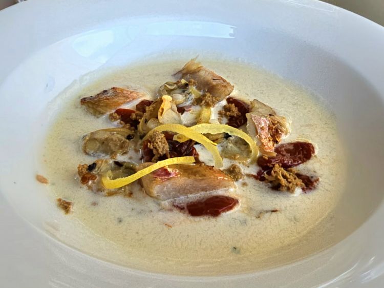 Triglia frollata 12 ore con zuppetta di mandorle, vongole, limone candito e bottarga. Piatto sferzante e di carattere che trova ritmo nei contrasti tra sapidità e dolcezza. C’è la nota iodata del pesce e dei frutti di mare, quella dolce e cremosa del frutto secco, l’acidità dell’agrume e l’intensità sapida della bottarga. Gioco di consistenze al palato