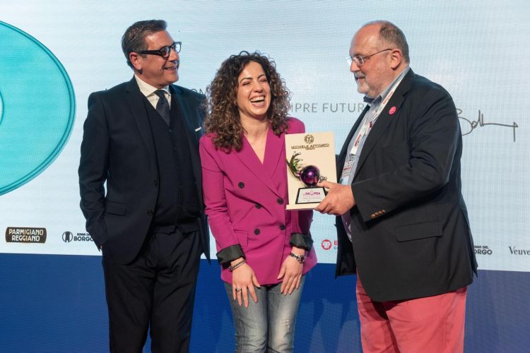 La Tropea Experience è stata protagonista anche nella cornice dello scorso congresso Identità Milano 2022. Nella foto, Daniele Cipollina e Carmen Giampà - rispettivamente responsabile comunicazione e marketing e imprenditrice del Consorzio Cipolla Rossa di Tropea Calabria Igp - con Paolo Marchi al momento della consegna a Niko Romito - in collegamento streaming - del premio Cipolla d’argento, scultura realizzata dal maestro crotonese Michele Affidato
