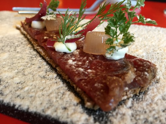 Marinated beef loin on black malt bread, sweet onion, smoked cheese and powdered vinegar, served at Tickets