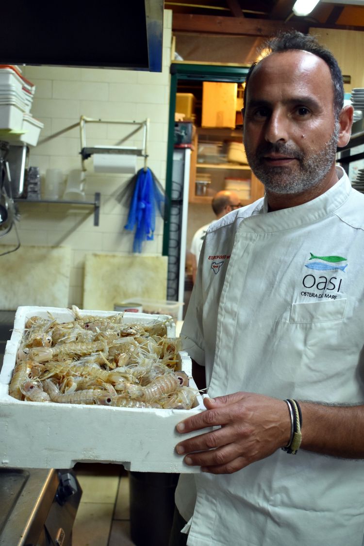 Giovanni Morello con una cesta di canocchie appena consegnate. «L'Oasi è un porto di mare, arriva pesce appena pescato in continuazione»
