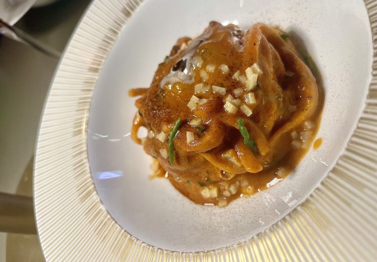 Linguina alla paprika affumicata, chimichurri di alghe e canocchie, limone fermentato, salicornia
Il nido di linguine - trafilate in bronzo da Biuso con aggiunta di paprika nell'impasto - gronda un sugo molto saporito che è il risultato di un battuto di canocchie, crostaceo simbolo di Romagna, e le alghe mauro dalla Sicilia, in una riedizione particolare del chimichurri, la salsa verde con cui gli argentini sono soliti marinare le carni della parrilla. I cubetti di limone fermentato aggiungono attenuate acidità citriche. Generosità, sapori
