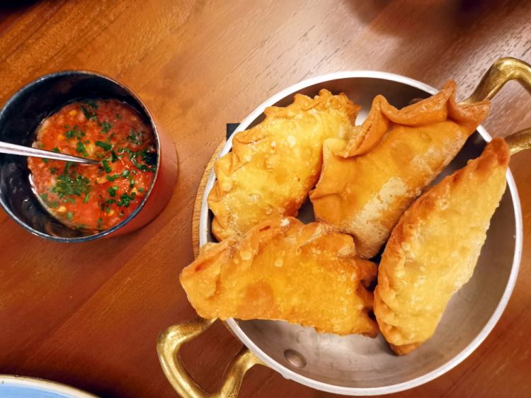 Empanadas. Non possono mancare nella cucina casalinga di un argentino. Quelle proposte a Casa Fuego sono ripiene di carne, cumino, cipolle, peperoni, paprika e ají tritato oppure vegetariane con mais, mozzarella e besciamella, che in Argentina si chiamano humitas. Sono servita con una salsa llajua, tipica del nordovest argentino: pomodoro grattugiato, succo di lime, scalogno, sale, ajì tritato
