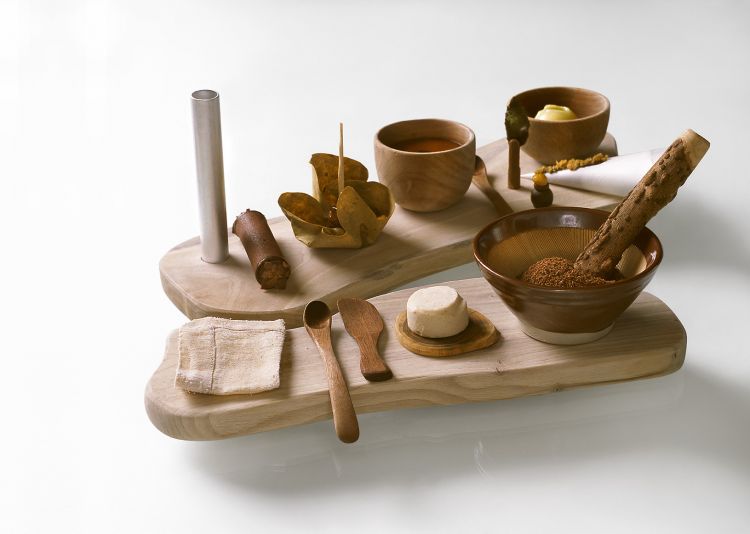 2005 - Gioccolato
«In un ristorante cinese a Tokyo ci servirono del sesamo in un mortaio di coccio dentellato. Da subito pensai al Gioccolato e affascinato dalla possibilità di far partecipare il commensale alla realizzazione del suo dolce, ne acquistai 35 pezzi. Volevo contrastare la levità dell’anno precedente con un dolce assolutamente materico. Il calore del legno e del coccio, il cornetto da pasticceria, il tessuto intriso di alcool, il cannolo da suggere, erano elementi che riportavano alla rudimentalità. Un gioco scandito in due tempi, un’interruzione congiunta dalle basi combacianti dei due supporti. La carnosità delle olive, la fibrosità della menta e la setosità del mosto cotto, conferivano naturalezza alla proposta. Un gioco interrotto, poi proseguito, vedeva trasformare ogni cliente in autore di una pietanza che andava al di là dei sapori; si ripristinava infatti un ordine di rapporto uomo-materia quasi primitivo».