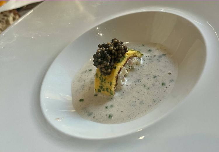 Zuppa di ranocchi al vino, trota affumicata e caviale di senape
Un piatto che nasce dalla zuppa contadina delle tradizioni contadine lombarde («il brodetto di ranocchi raccontato da Luigi Veronelli», spiega Sacchi). E' una zuppa di rane al vino con una frittata sottile alle erbe, la farcia di rane e di trota bianca affumicata. Sopra c'è del "caviale" di senape, cioè grani cotti in un brodo di pesce alla brace e nero di seppia. La zuppa di vino, rinforzata all'ultimo con uova e panna, è un'alchimia figlia della tradizione austro-ungarica, storicamente piuttosto influente nelle tradizioni meneghine e lombarde
