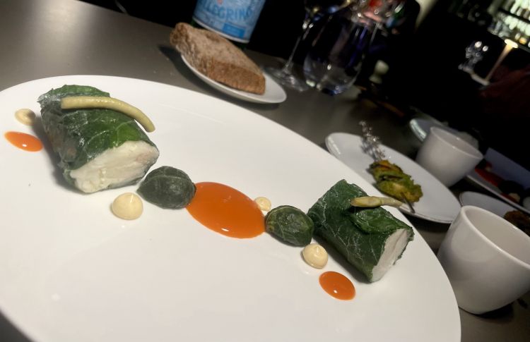 Coda di rospo, tenerumi, cozze e masala
La coda di rospo, specialità piuttosto popolare in Romagna, è cotta in bassa temperatura e servita in due tranci generosi. Accanto, c'è un piccolo spiedini di cozze dell'Adriatico avvolte da Biuso in un masala, mix di spezie locali e indiane, passione del cuoco. Nel bicchierino, un ristretto di tenerumi (foglie e germogli di una particolare zucchina siciliana)
