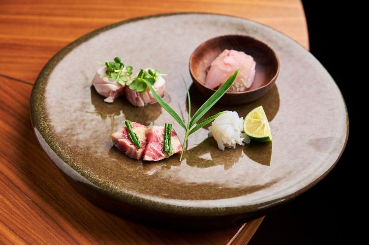 Otsukuri
E' la prima selezione di quattro specialità di sashimi a doppia firma. A destra, i due assaggi di chef Ishida: sopra del Pagro (sorta di dentice) con irizake, una gelatina le cui origini storiche affondano nella notte dei tempi (periodo Muromachi, oltre mezzo millennio fa), ottenuta marinando e bollendo dell'umeboshi (prugna fermentata) nel sake; sotto della Seppia a julienne con cristalli di sale e sudachi (lime) da spremere sopra. A sinistra, gli assaggi più grassi e "ruffiani" di Suzuki san: sopra Cernia shabu shabu (leggermente scottata), sotto Ventresca di tonno tataki affumicato al fieno con salicornia
