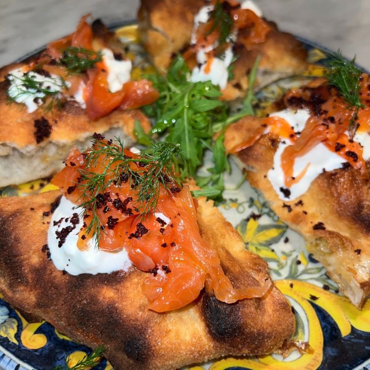 Pizza in doppia cottura con trota salmonata affumicata, rucola, stracciatella e polvere di olive